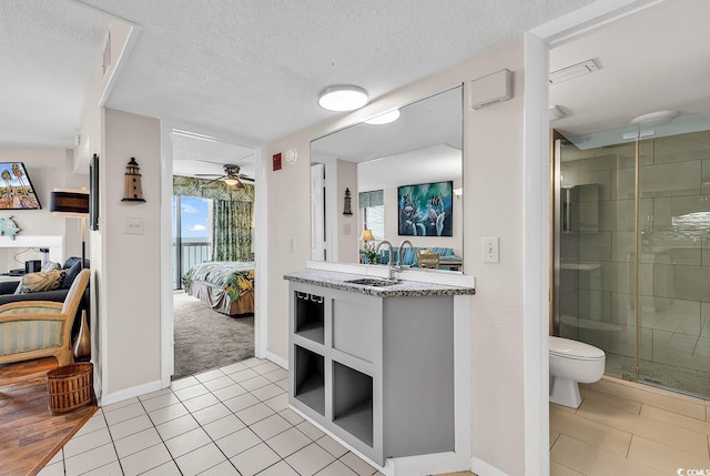 bathroom with vanity, ceiling fan, tile patterned flooring, toilet, and a shower with shower door