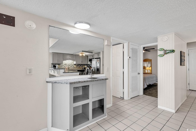 kitchen with backsplash, gray cabinetry, stainless steel fridge, and light tile patterned flooring