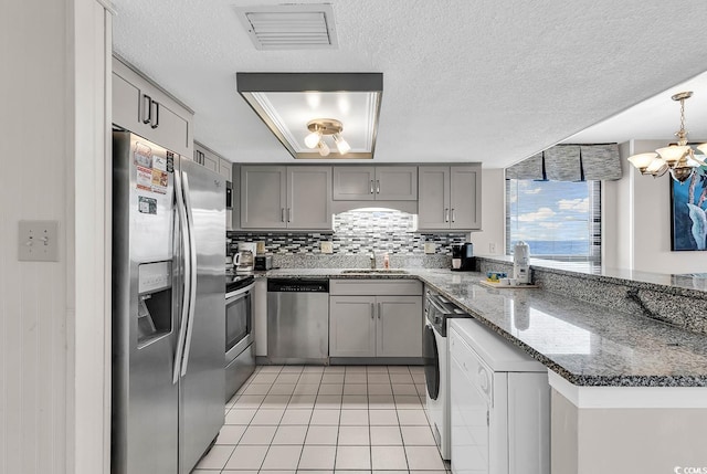 kitchen featuring kitchen peninsula, pendant lighting, decorative backsplash, light tile patterned floors, and appliances with stainless steel finishes