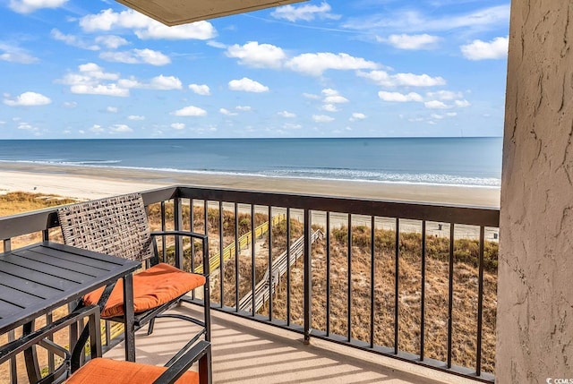 balcony featuring a view of the beach and a water view