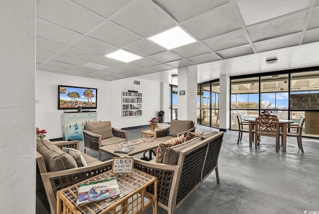 living room featuring a paneled ceiling and concrete floors