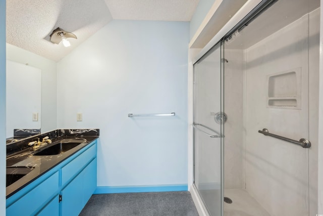 bathroom with vaulted ceiling, vanity, an enclosed shower, and a textured ceiling