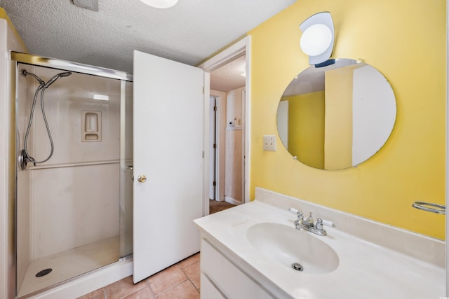 bathroom featuring vanity, a textured ceiling, tile patterned floors, and a shower with shower door