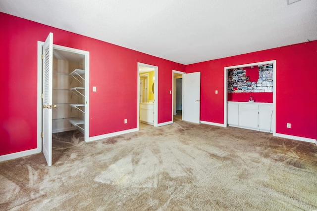 unfurnished bedroom featuring carpet flooring, a walk in closet, and ensuite bathroom