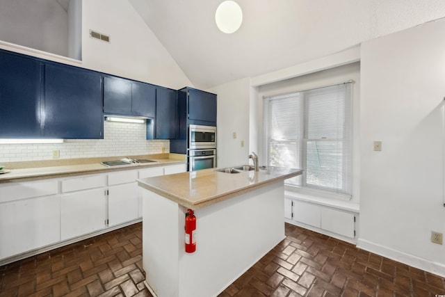 kitchen with backsplash, stainless steel appliances, a kitchen island with sink, sink, and white cabinets