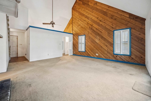 unfurnished living room featuring carpet, high vaulted ceiling, ceiling fan, and wood walls