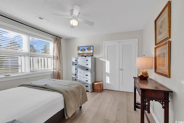 bedroom featuring ceiling fan, a textured ceiling, a closet, and light wood-type flooring