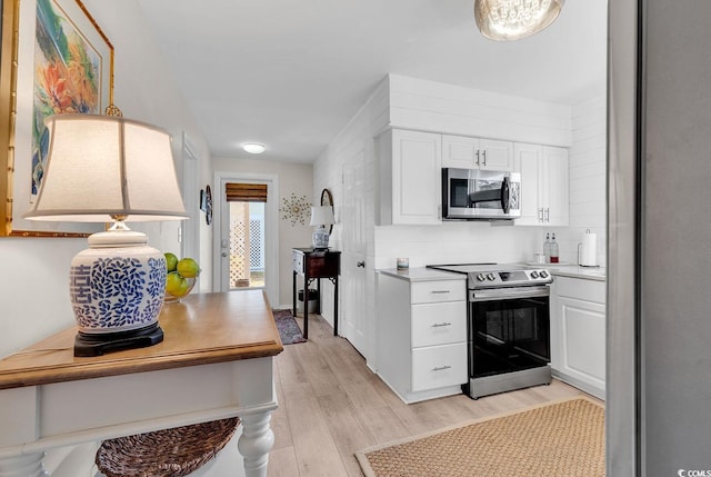 kitchen featuring white cabinetry, appliances with stainless steel finishes, pendant lighting, and light hardwood / wood-style floors