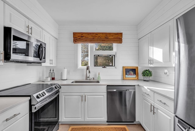 kitchen with sink, backsplash, white cabinets, and appliances with stainless steel finishes