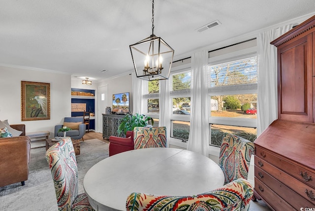 dining space featuring an inviting chandelier, ornamental molding, and a textured ceiling