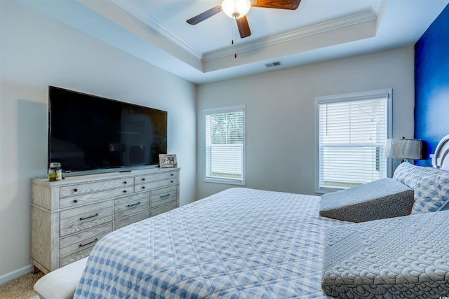 carpeted bedroom featuring ceiling fan, ornamental molding, and a raised ceiling