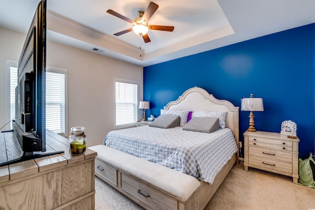 carpeted bedroom featuring ceiling fan and a tray ceiling