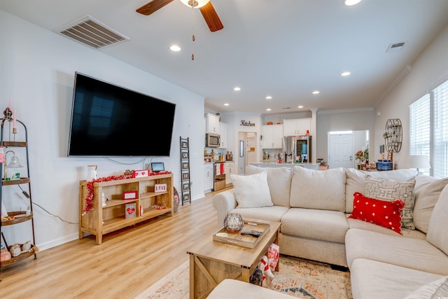 living room featuring ceiling fan, ornamental molding, and light hardwood / wood-style flooring