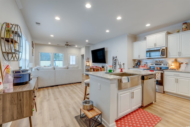 kitchen with white cabinetry, a center island with sink, ceiling fan, stainless steel appliances, and sink