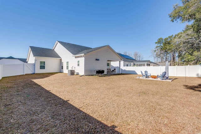 rear view of house with central air condition unit and a fire pit