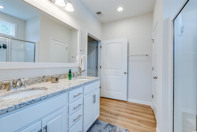 bathroom with wood-type flooring, walk in shower, and vanity