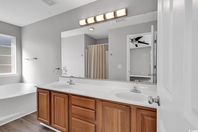 bathroom with a tub to relax in, ceiling fan, vanity, and wood-type flooring