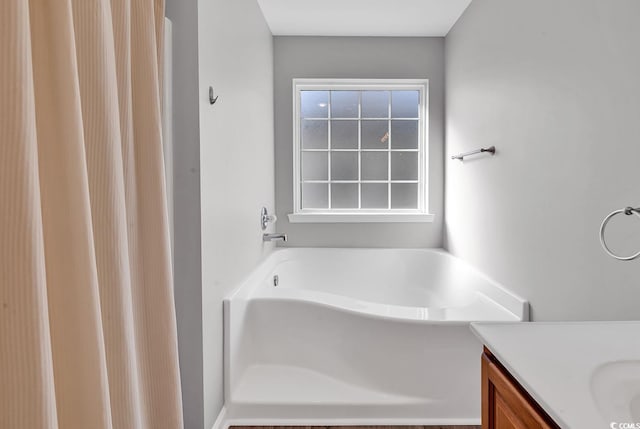 bathroom with plenty of natural light, a bath, and vanity