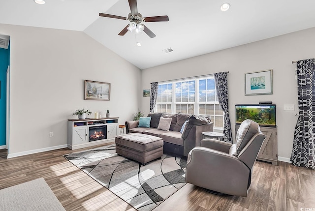 living room with ceiling fan, wood-type flooring, and vaulted ceiling