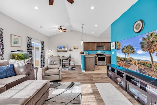 living room with ceiling fan, light wood-type flooring, and vaulted ceiling