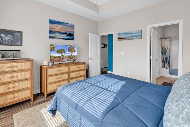 bedroom with ensuite bath and dark hardwood / wood-style floors