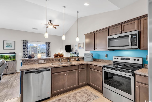 kitchen with kitchen peninsula, sink, stainless steel appliances, and decorative light fixtures