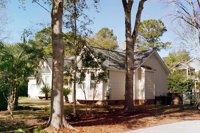 view of side of home with roof with shingles and crawl space