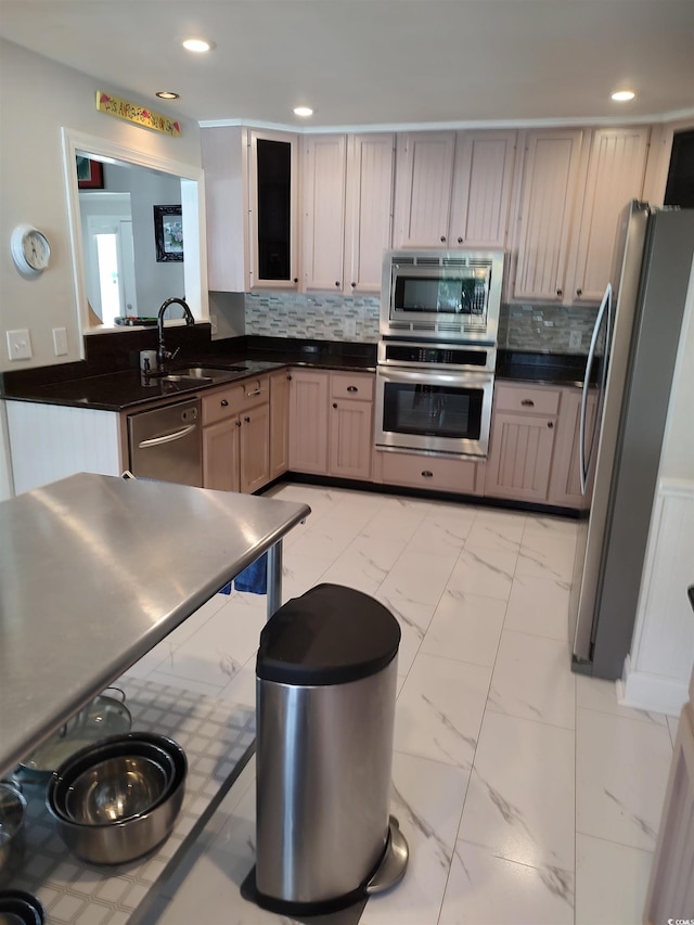 kitchen featuring marble finish floor, stainless steel appliances, dark countertops, backsplash, and a sink