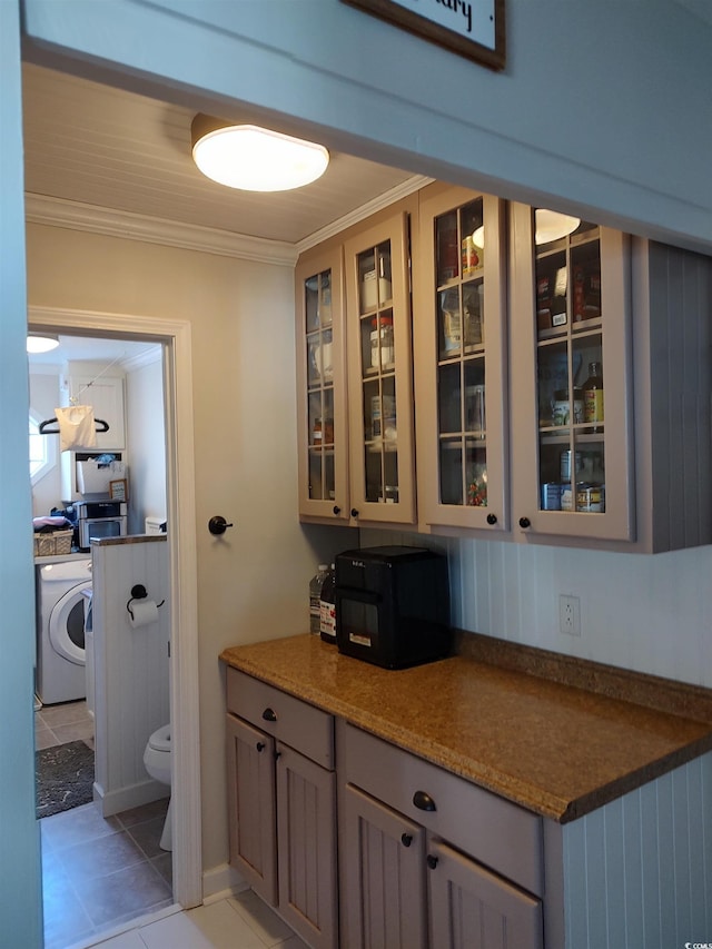 bar featuring washer / dryer, light tile patterned floors, and crown molding