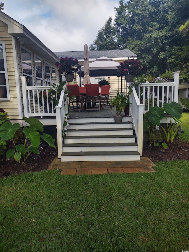 deck featuring outdoor dining space and a yard