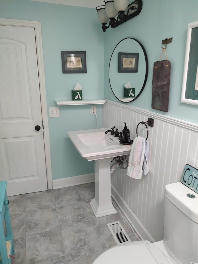 half bath featuring toilet, wainscoting, and visible vents