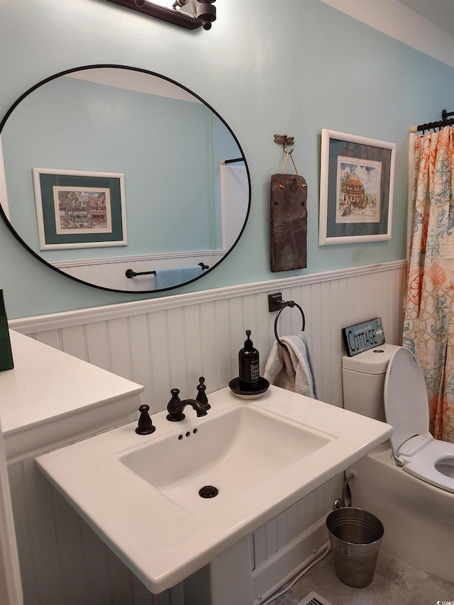 bathroom with wainscoting, a sink, and toilet