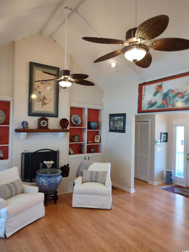 living area featuring high vaulted ceiling, a brick fireplace, beamed ceiling, and wood finished floors