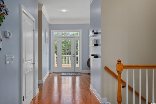 entryway with crown molding and light hardwood / wood-style floors