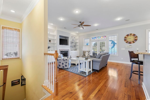 living room featuring french doors, ornamental molding, built in features, hardwood / wood-style flooring, and ceiling fan