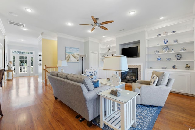 living room featuring crown molding, wood-type flooring, built in features, and french doors