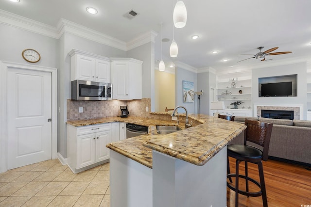 kitchen with appliances with stainless steel finishes, decorative light fixtures, a breakfast bar, and white cabinets