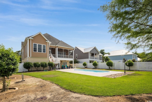 rear view of property with a fenced in pool, a patio, a sunroom, and a lawn