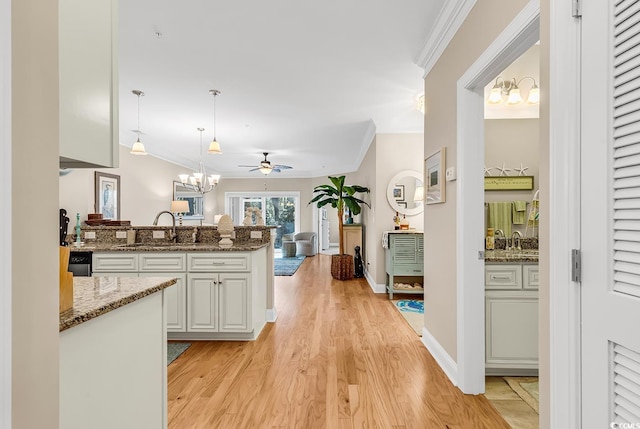 kitchen featuring hanging light fixtures, crown molding, sink, and light wood-type flooring