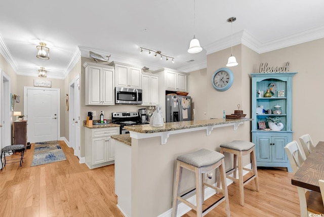 kitchen featuring a breakfast bar area, white cabinets, light stone counters, stainless steel appliances, and light wood-type flooring