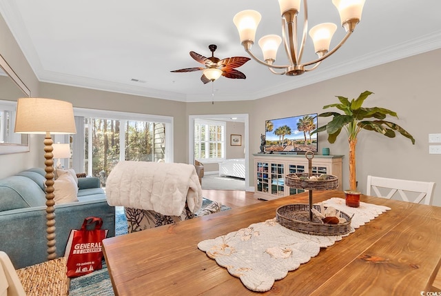 dining space with hardwood / wood-style floors, crown molding, and ceiling fan with notable chandelier