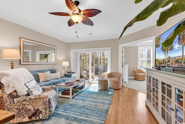 living room with light hardwood / wood-style flooring, ornamental molding, and ceiling fan