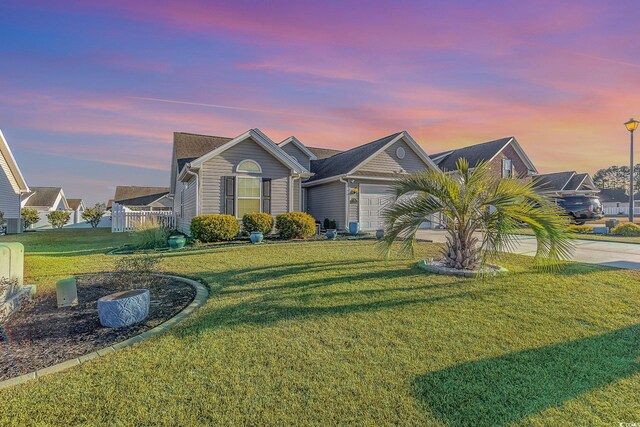 view of front of home with a garage and a yard