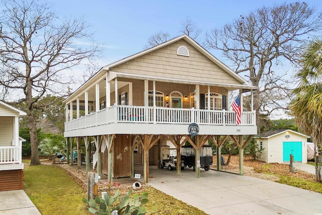 raised beach house with covered porch, a storage unit, and a carport