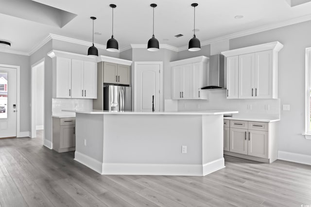 kitchen featuring stainless steel fridge with ice dispenser, a center island, decorative light fixtures, and wall chimney range hood