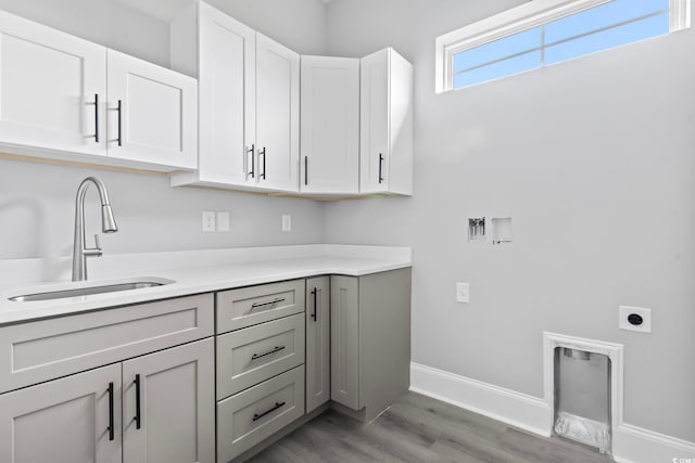 laundry area with cabinets, hardwood / wood-style floors, electric dryer hookup, and sink