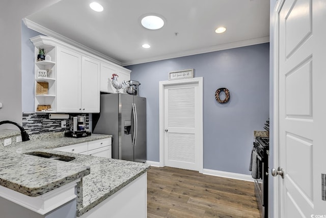 kitchen with sink, stainless steel appliances, light stone counters, kitchen peninsula, and white cabinets