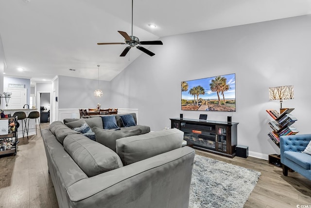 living room with light hardwood / wood-style floors, vaulted ceiling, and ceiling fan