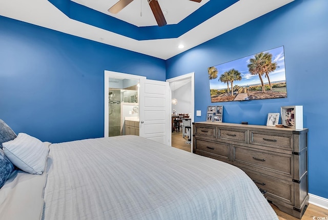 bedroom featuring light wood-type flooring, ensuite bathroom, and ceiling fan