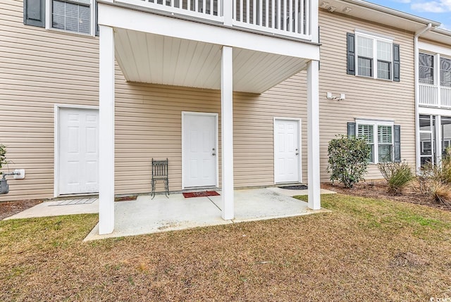 view of exterior entry with a lawn and a patio